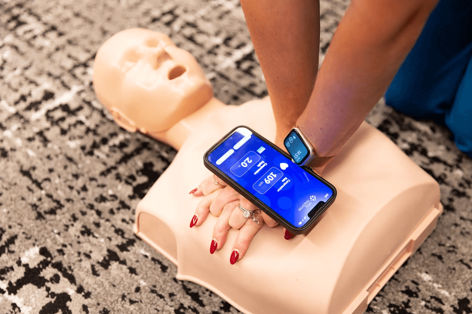 Practicing CPR on a manikin with the Relay Response app on a phone and smartwatch